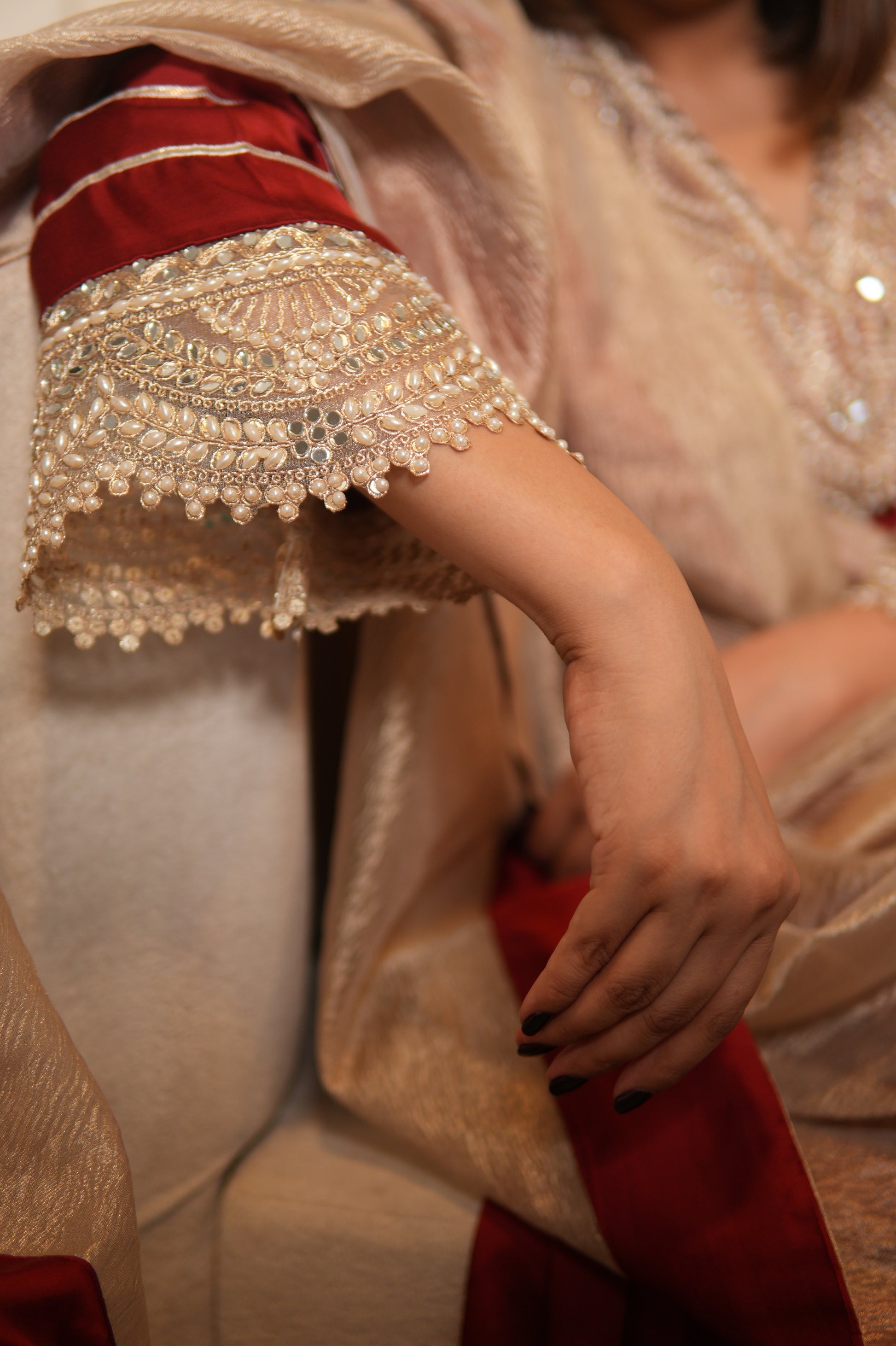 Close-up of a person wearing an ornate, red and gold garment with intricate patterns.