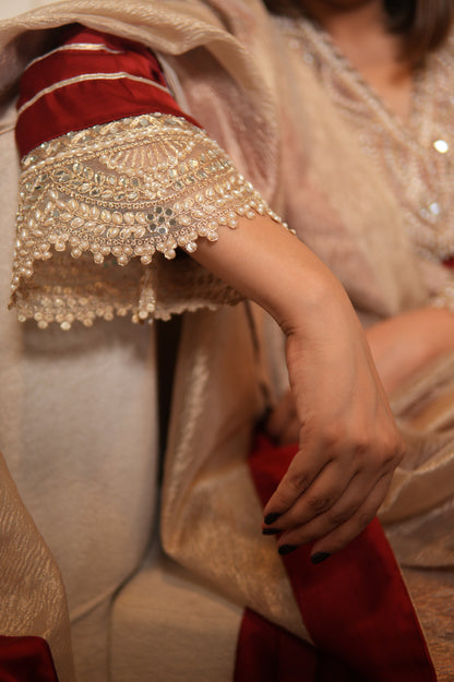 Close-up of a person wearing an ornate, red and gold garment with intricate patterns.
