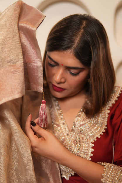 Woman in traditional attire highlighting a tassel on dupatta's edge.