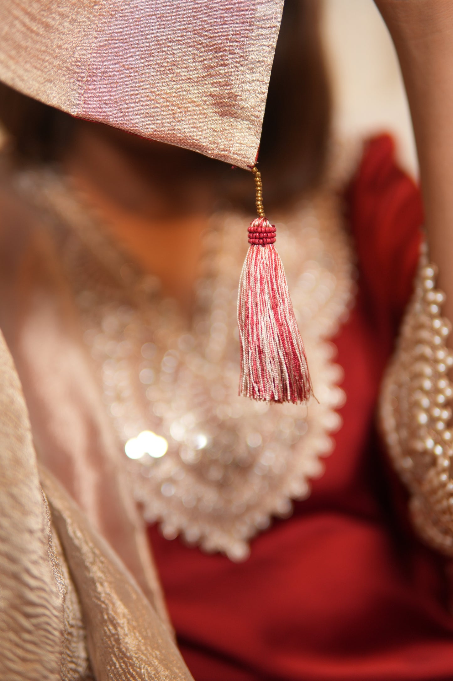 Close-up of a decorative fabric with a tassel and beads, possibly from a traditional garment.