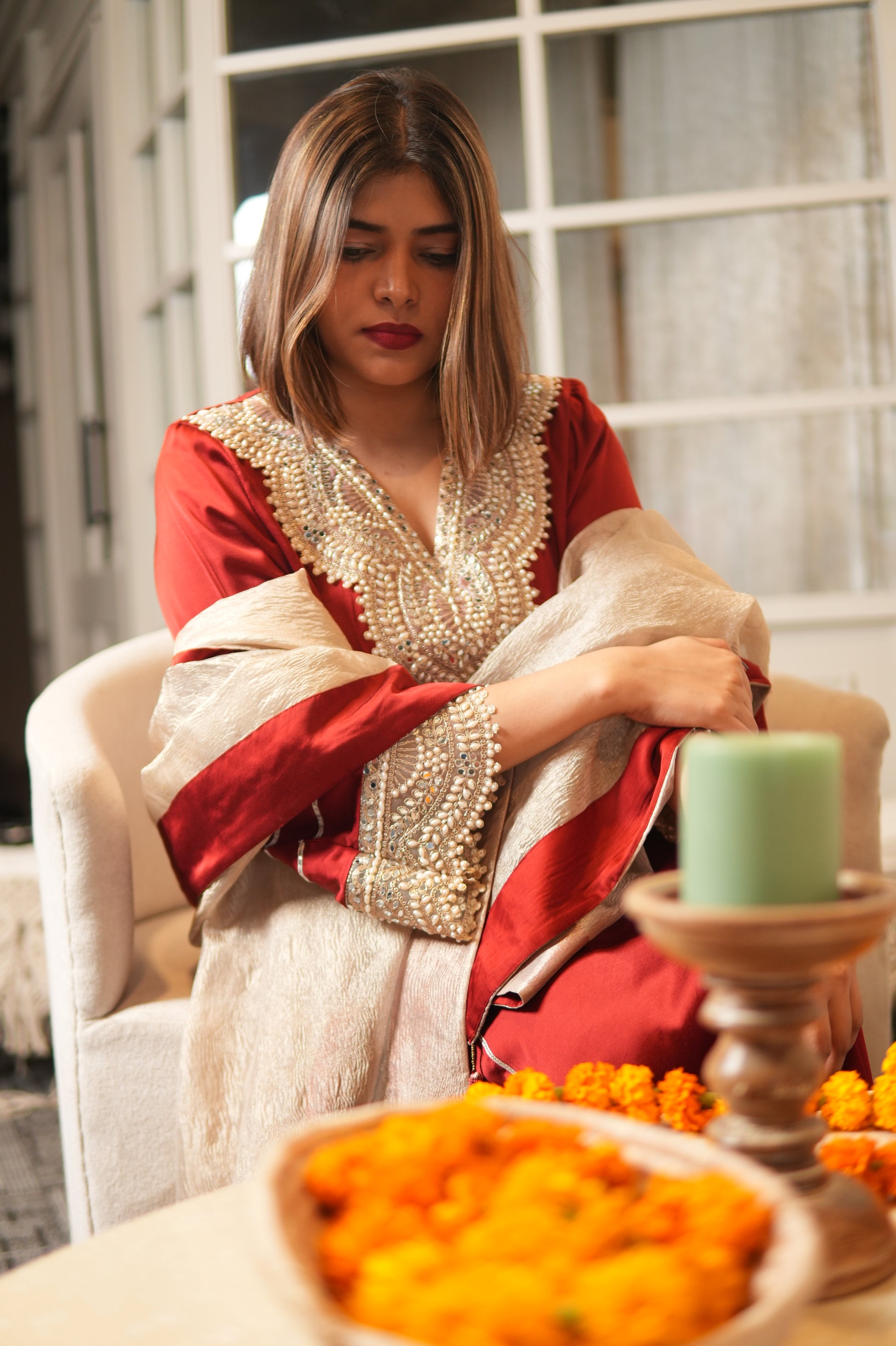 Woman in a traditional outfit holding a floral pot indoors