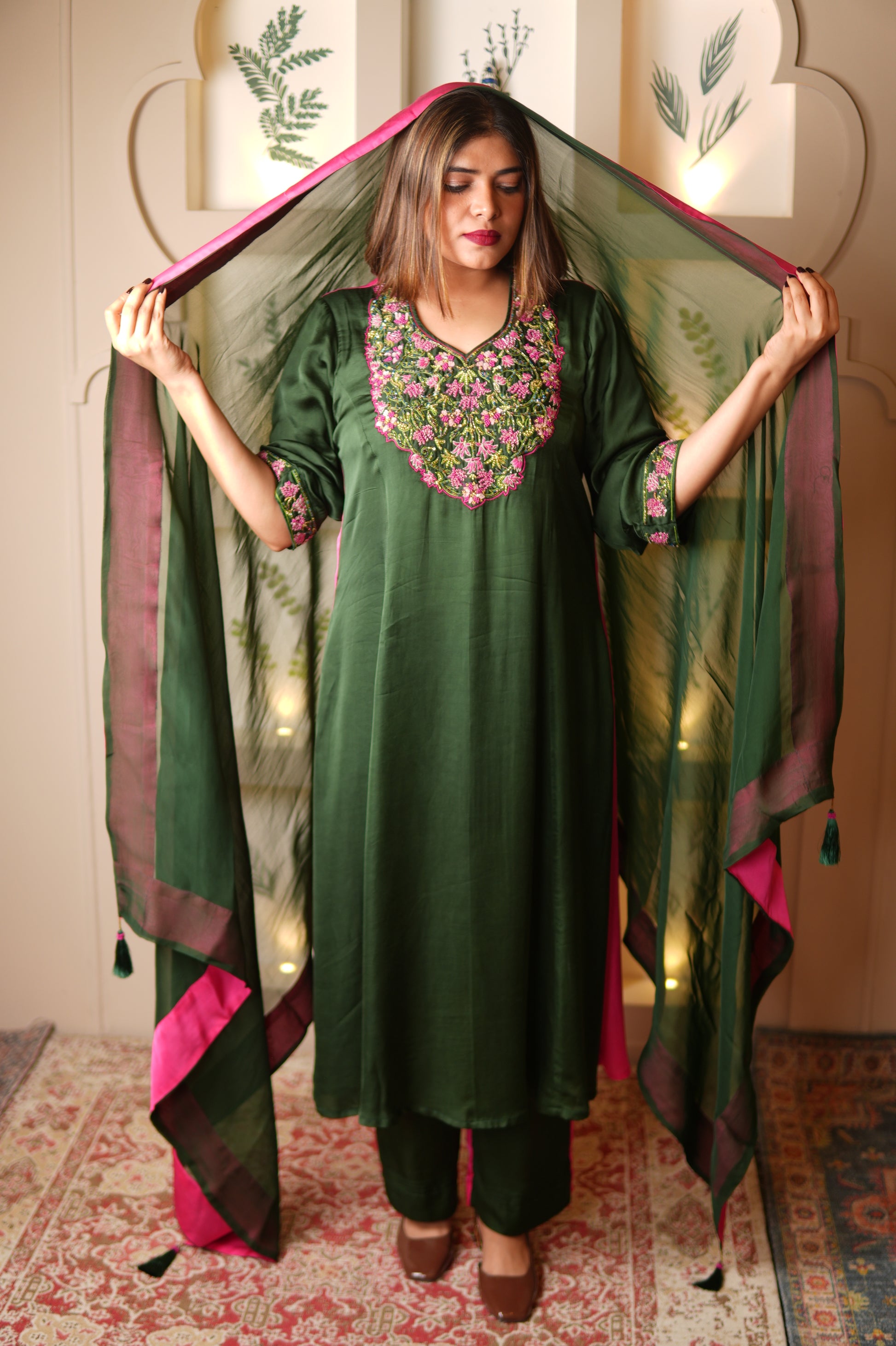 Woman holding a green dupatta with pink border indoors