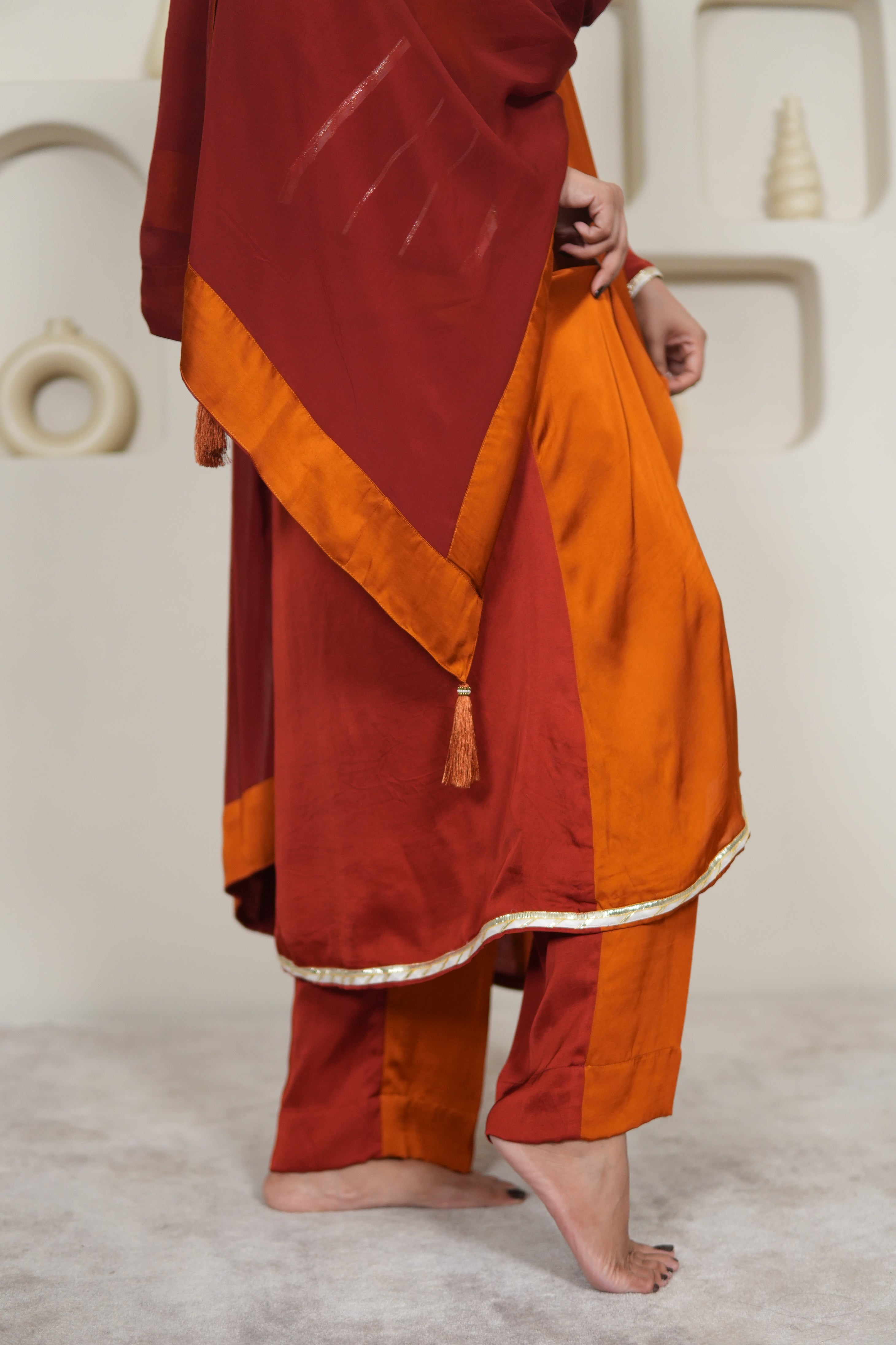 Person wearing a traditional outfit with orange and red colors on a light background