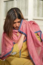 Woman wearing a pink and yellow traditional outfit with a decorative brooch.