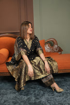 Woman in a patterned dress sitting on an ornate chair with a blurred background